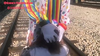 Извращенец в костюме клоуна на шпалах трахает горло соске